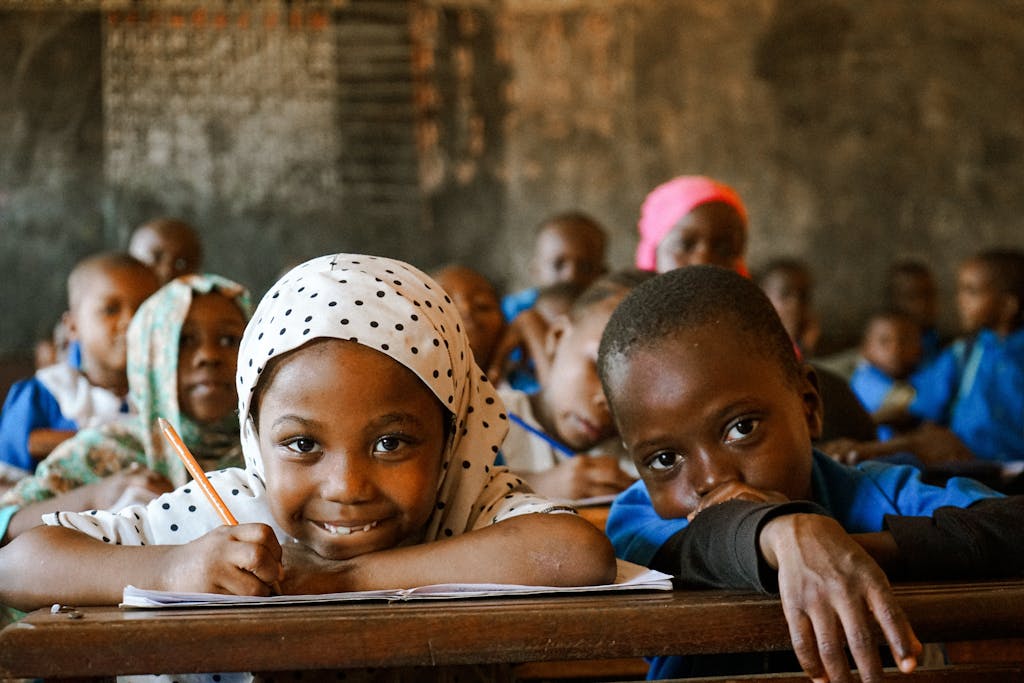 Des élèves congolais souriants en classe, écrivant dans leurs cahiers